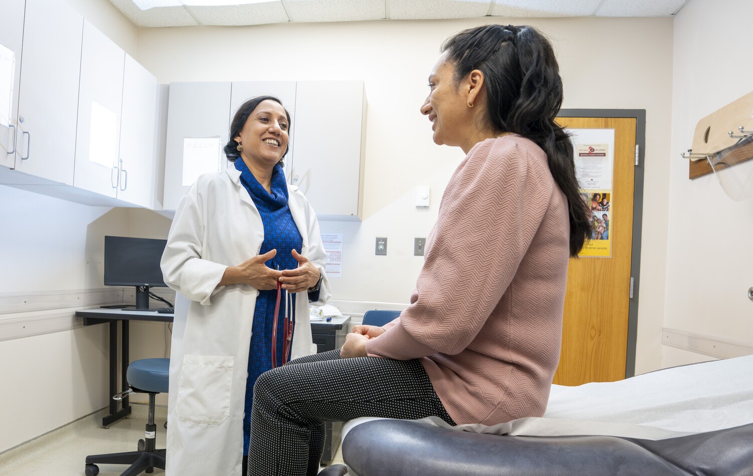 CUHCC physician and CEO Roli Dwivedi, MD, has a friendly chat with patient and CUHCC board of directors member Ines Lazo in a clinical exam room