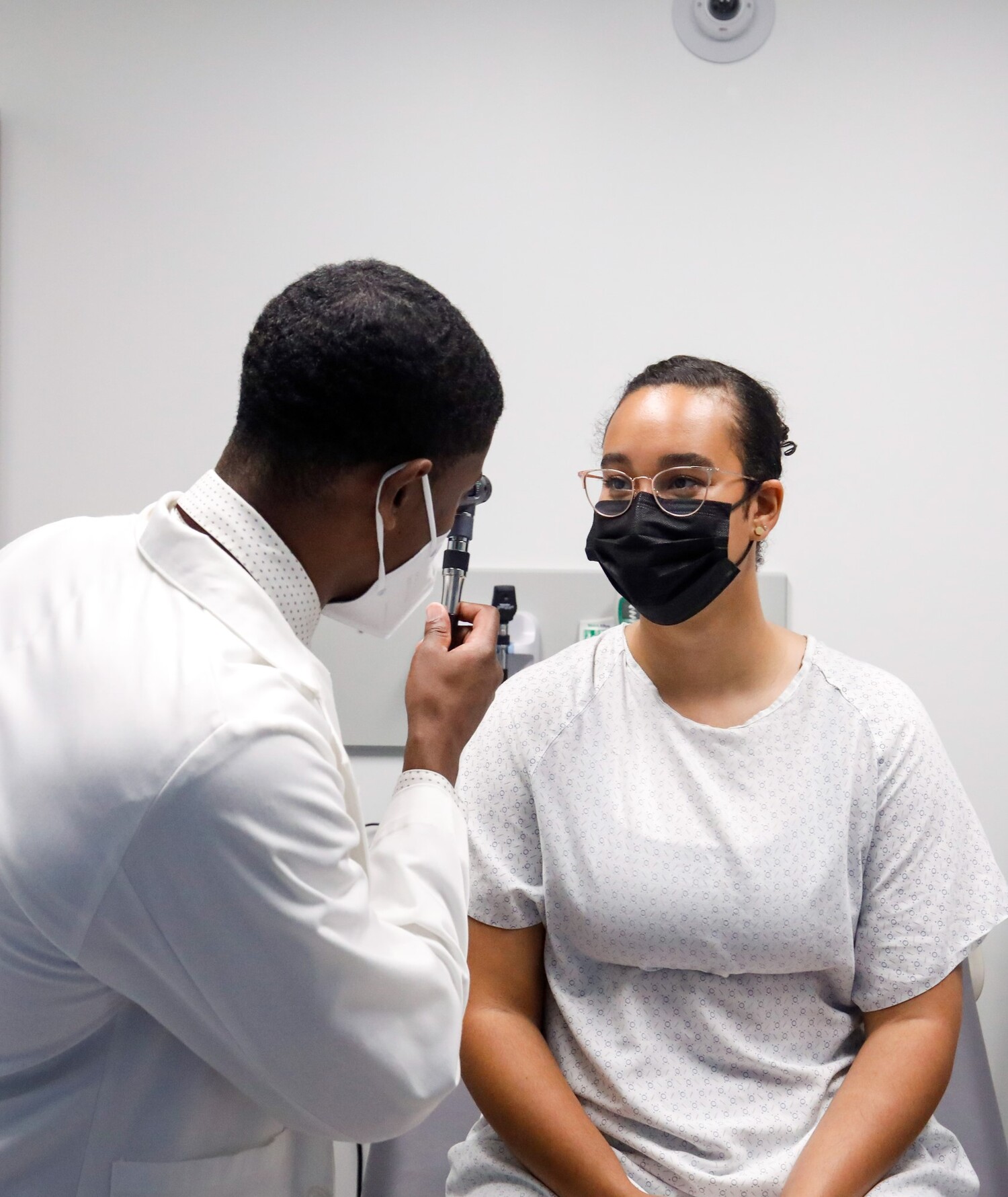 a medical student uses an otoscope during a mock patient exam