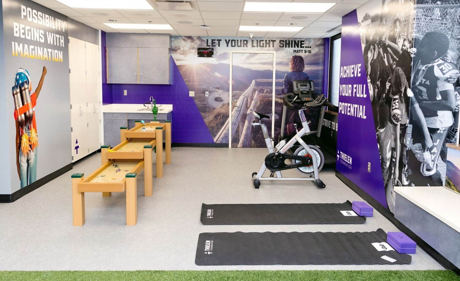 a wide shot of the Thielen Foundation Workout Room, showing a water table, exercise bike, and yoga mats