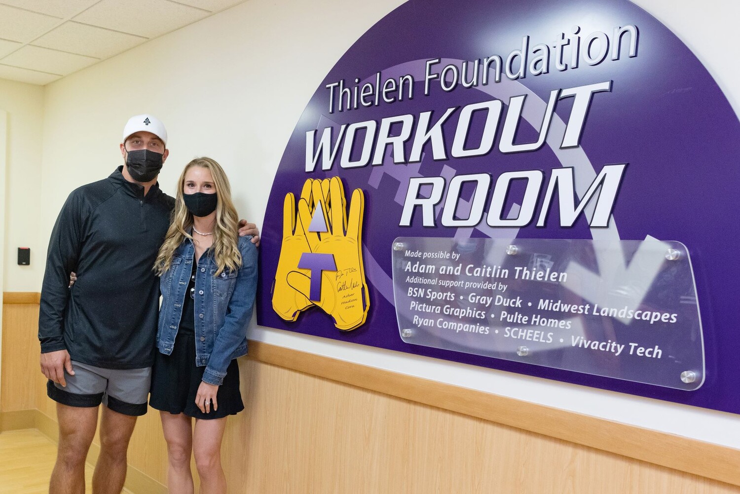 Adam and Caitlin Thielen pose by the sign to the new Thielen Foundation Workout Room