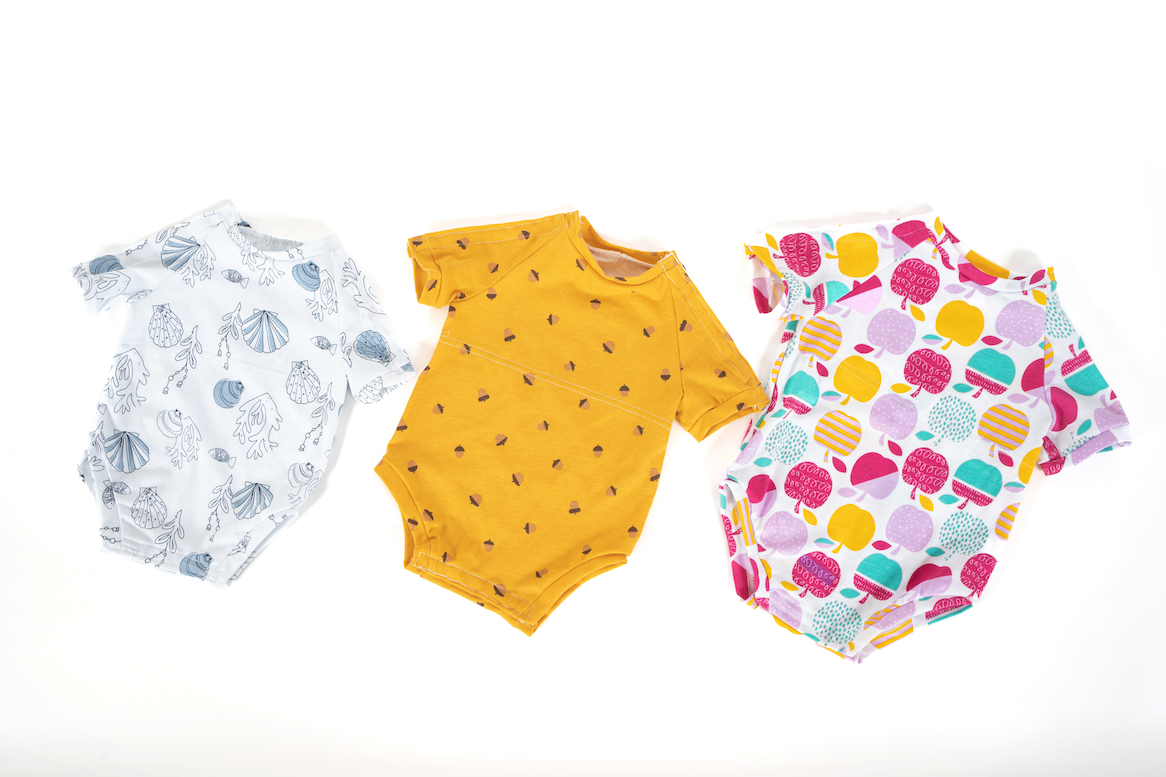 three specially designed onesies with colorful designs