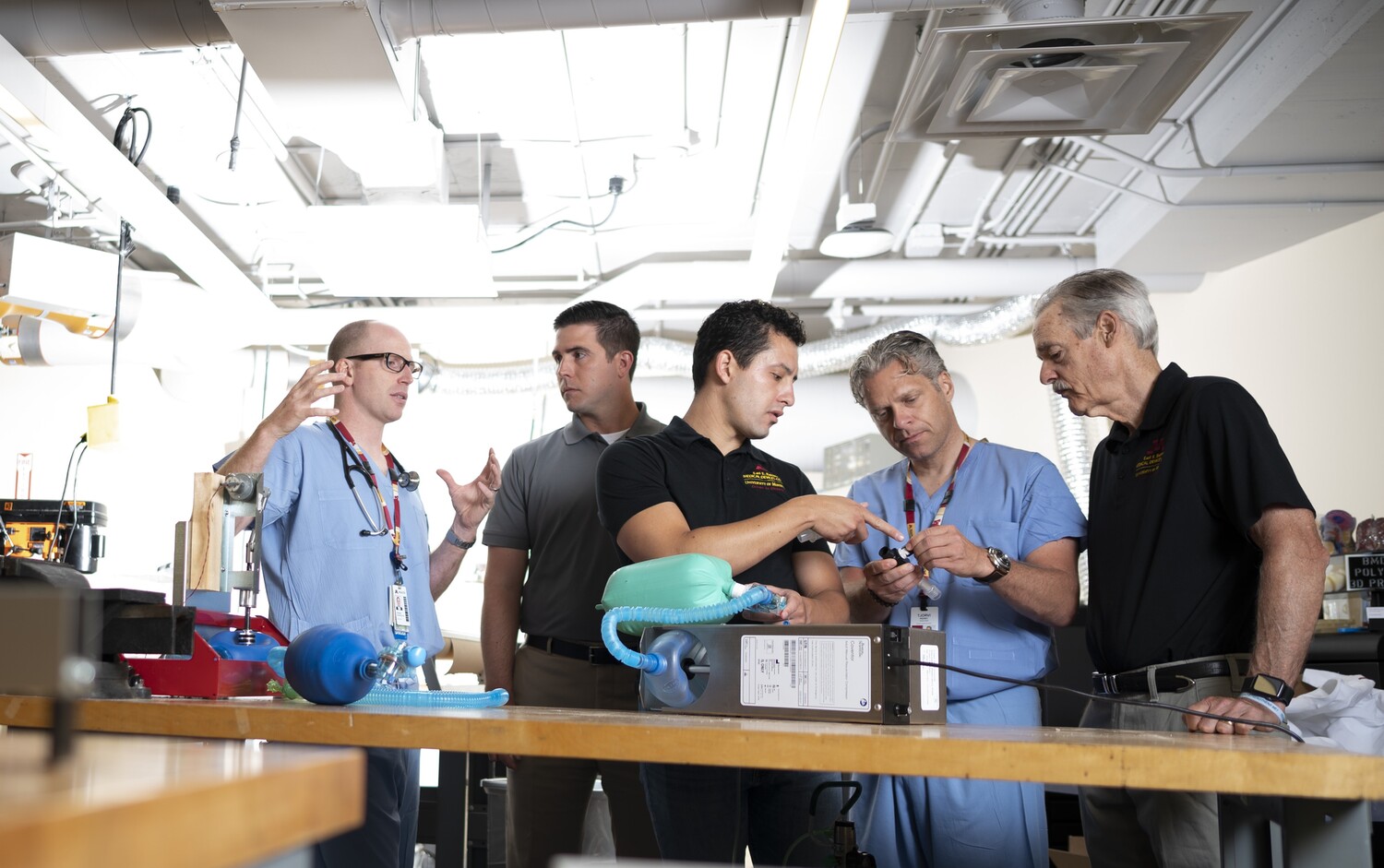 A photo of a group of physicians and engineers standing over the Coventor, a low-cost ventilator